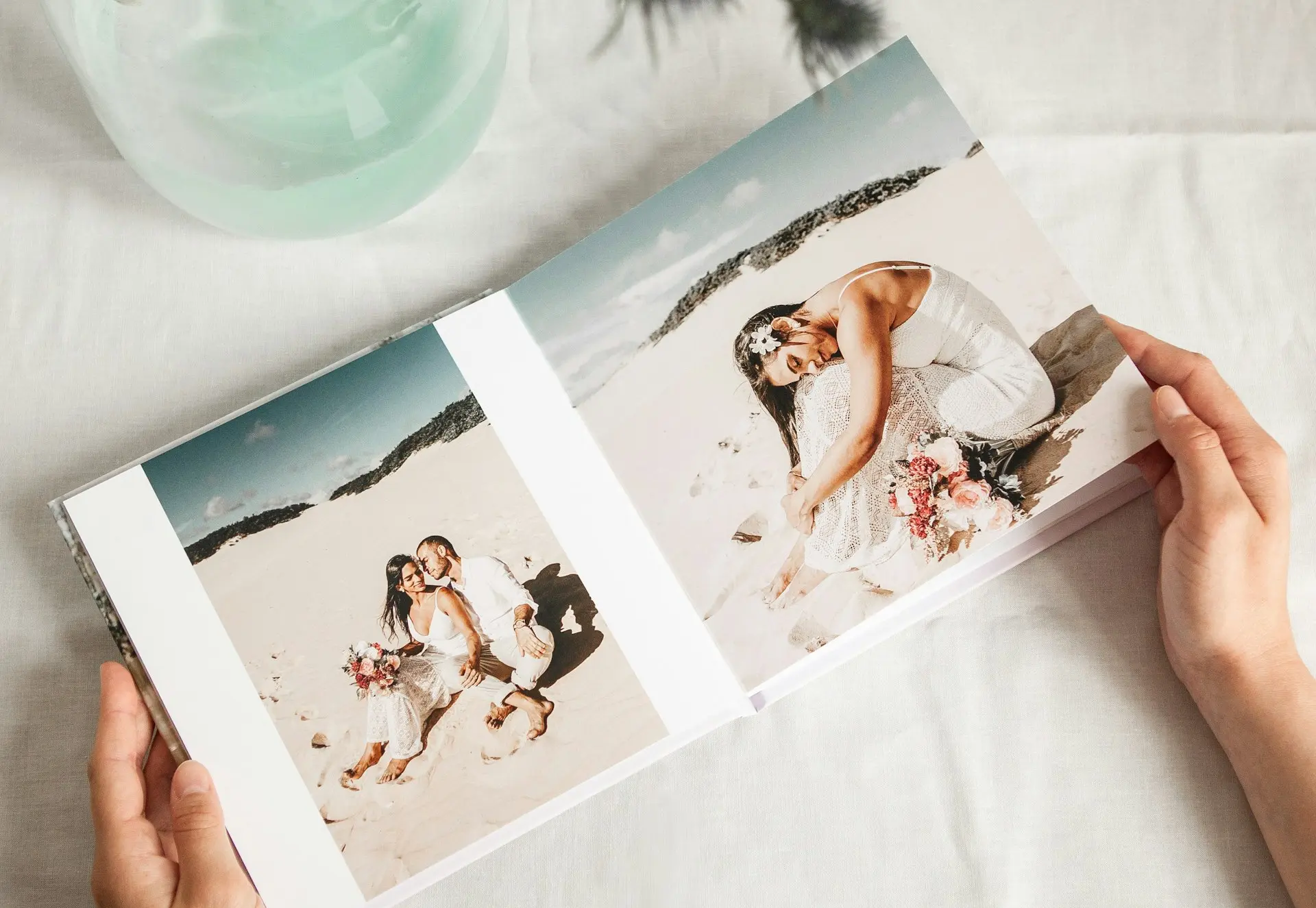 a person holding a photo book open to a picture of a bride and groom